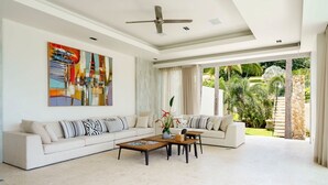 A spacious living room with a large sofa, coffee table, and a ceiling fan.