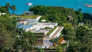 Una casa moderna con terraza en la azotea, rodeada de exuberante vegetación y vista al mar.