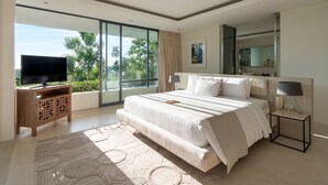 Un dormitorio moderno con una cama grande, un televisor de pantalla plana, un ventilador de techo y un amplio ventanal con vistas a la vegetación.
