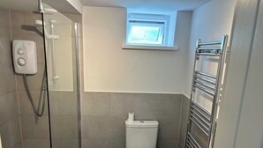 Une salle de bain avec une douche à parois de verre, des toilettes et un lavabo.