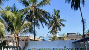 Una piscina con borde de azulejos, rodeada de palmeras y una valla blanca.