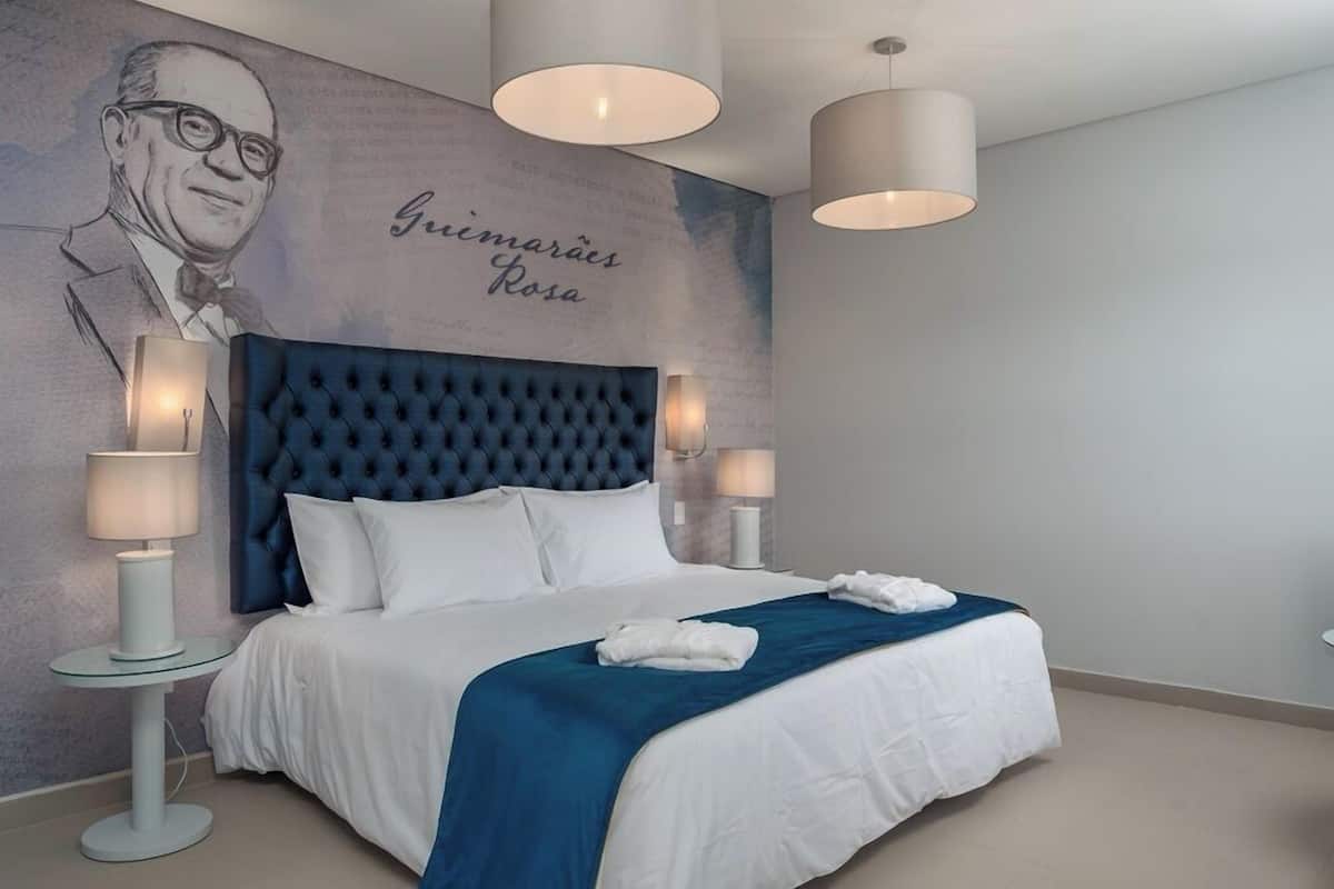 Een moderne hotelkamer met een groot bed, een gestuufd hoofdeinde en een muurschildering.