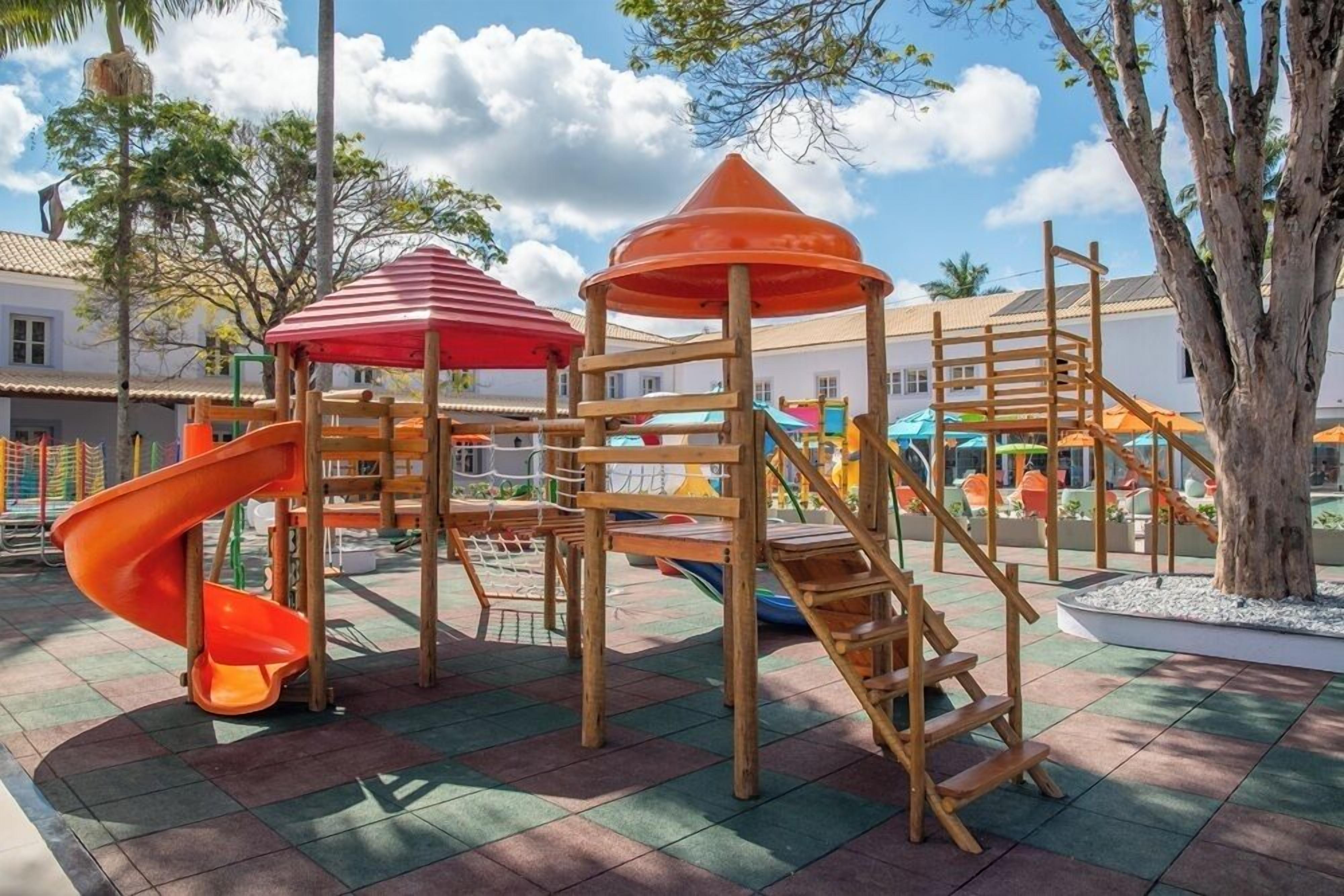 A playground with a slide, climbing structures, and a covered area.