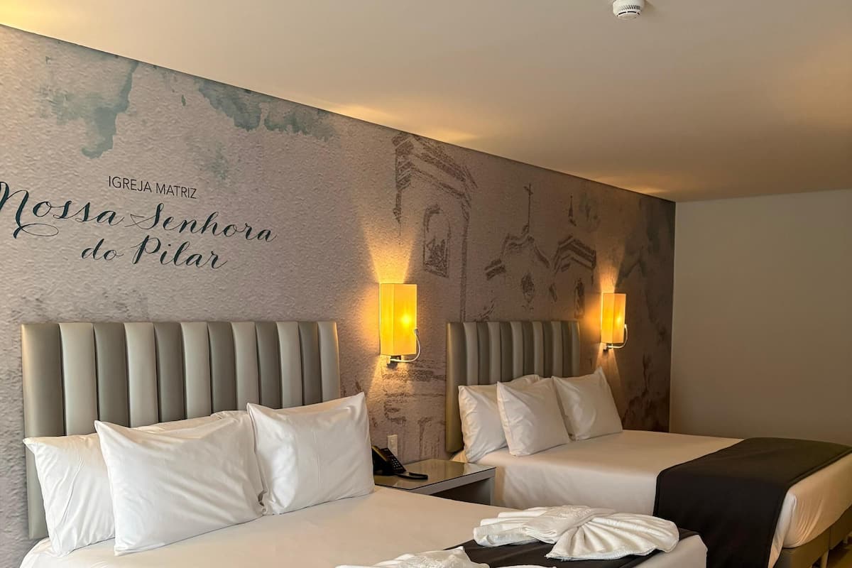 Een hotelkamer met twee bedden, een muurschildering en een rookmelder aan het plafond.