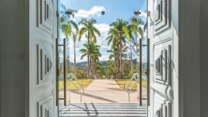 Une vue à travers une porte, avec un chemin pavé qui mène à des palmiers et à un paysage lointain.