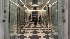 Un couloir doté de portes en verre, d’un sol à carreaux et d’une statue centrale.