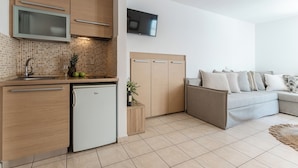 A modern kitchen with a built-in microwave, a small refrigerator, and a tiled backsplash. - KALLISTI STUDIOS (Naxos)