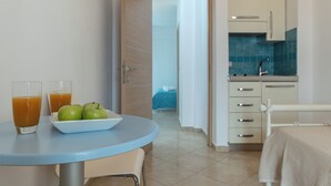 A room with a round table, two glasses of orange juice, and a bowl of green apples. - KALLISTI STUDIOS (Naxos)