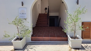 A building entrance with a sign for 'Kallisti Studios', a staircase, and two potted olive trees. - KALLISTI STUDIOS (Naxos)