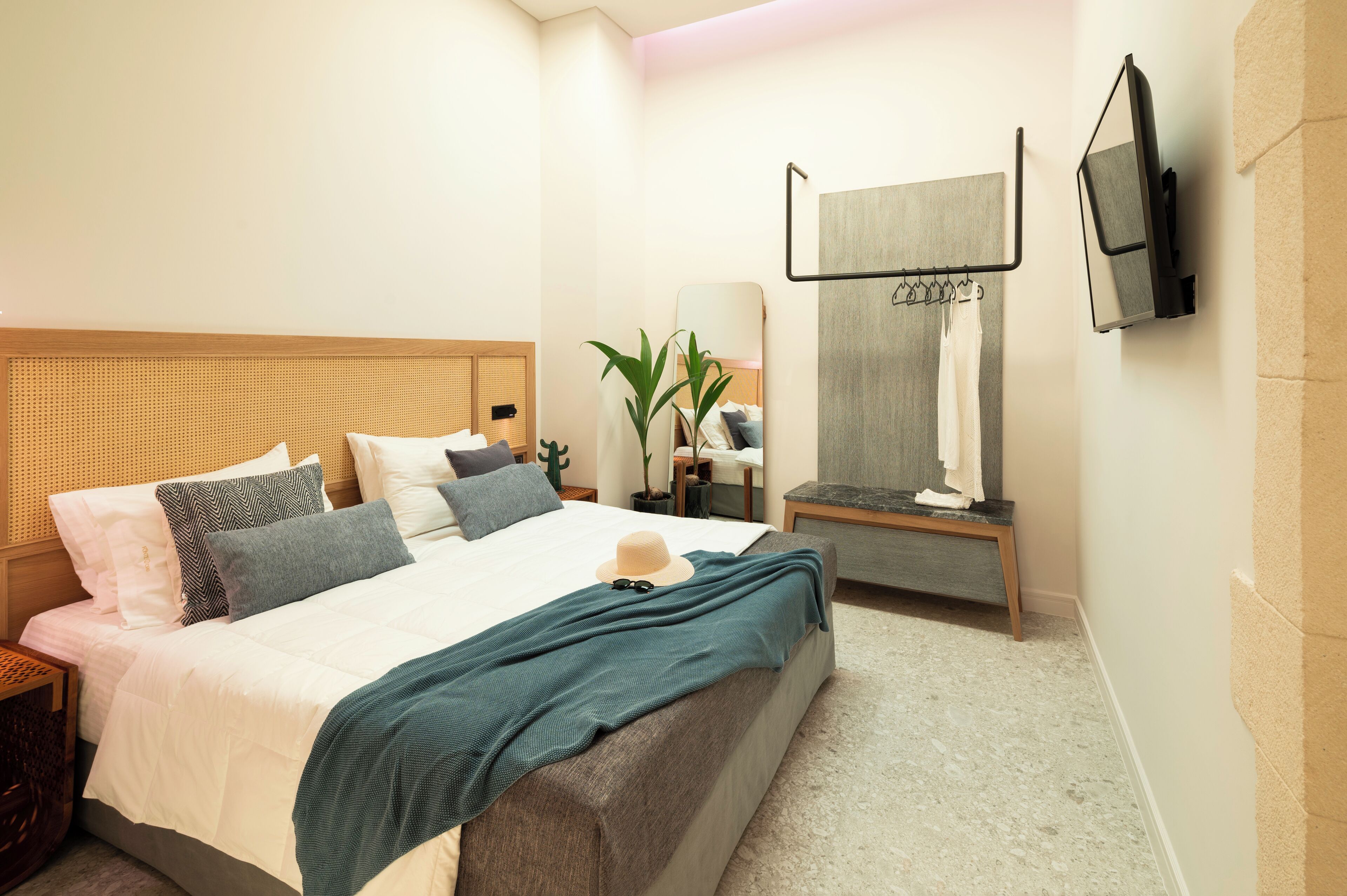 Een moderne hotelkamer met een groot bed, een nachtkastje, een spiegel en een aan de muur bevestigde televisie.