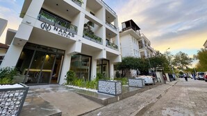 A multi-story hotel with balconies, a clear sky, and a paved walkway.