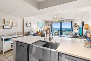Una cocina moderna con una isla grande, lavavajillas y vista al océano.