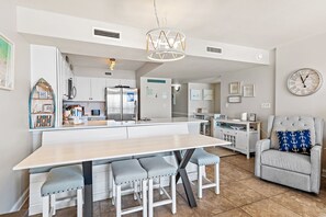 Una cocina moderna con una isla central, armarios blancos y una zona de comedor con banco.
