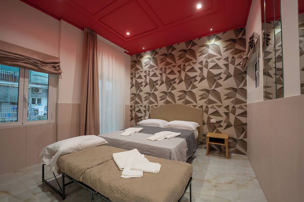 A hotel room with a bed, a bench, and a geometric-patterned wall.