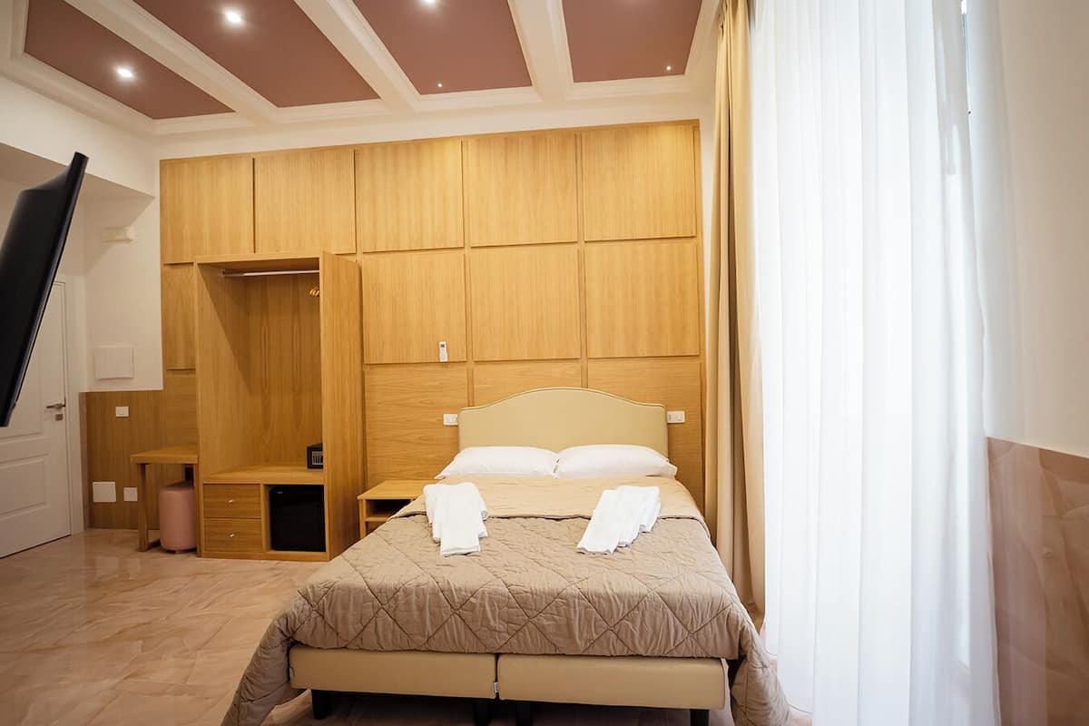 A bedroom with a bed, wooden wardrobe, and a bench.