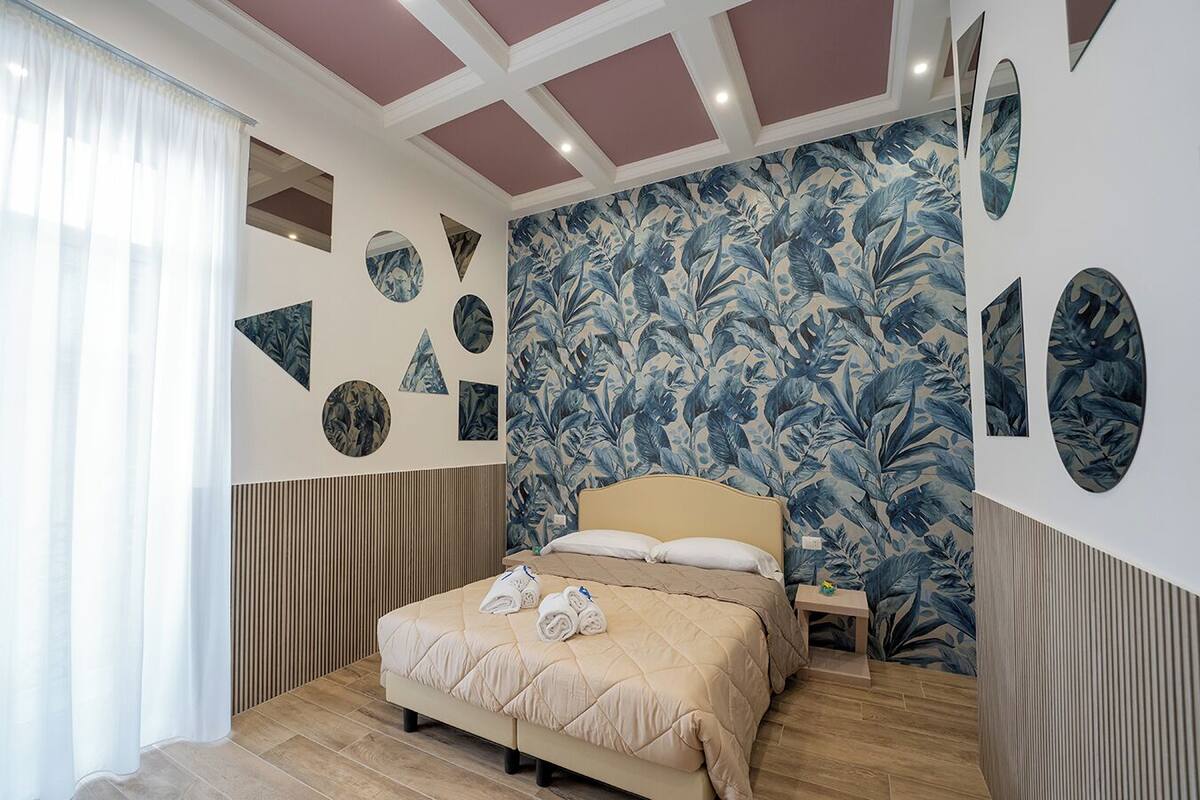 A bedroom with a bed, a nightstand, and a wall with circular and triangular cutouts.