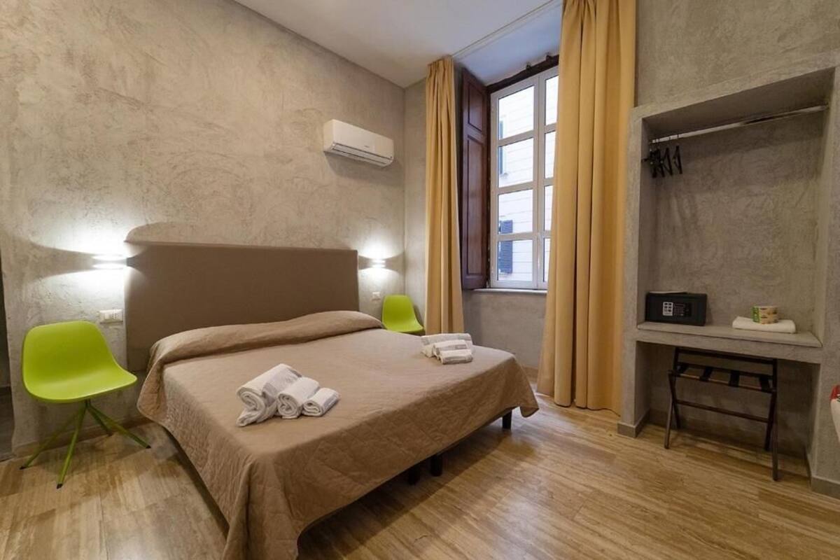 A hotel room with a bed, two chairs, a desk, and a window with curtains.