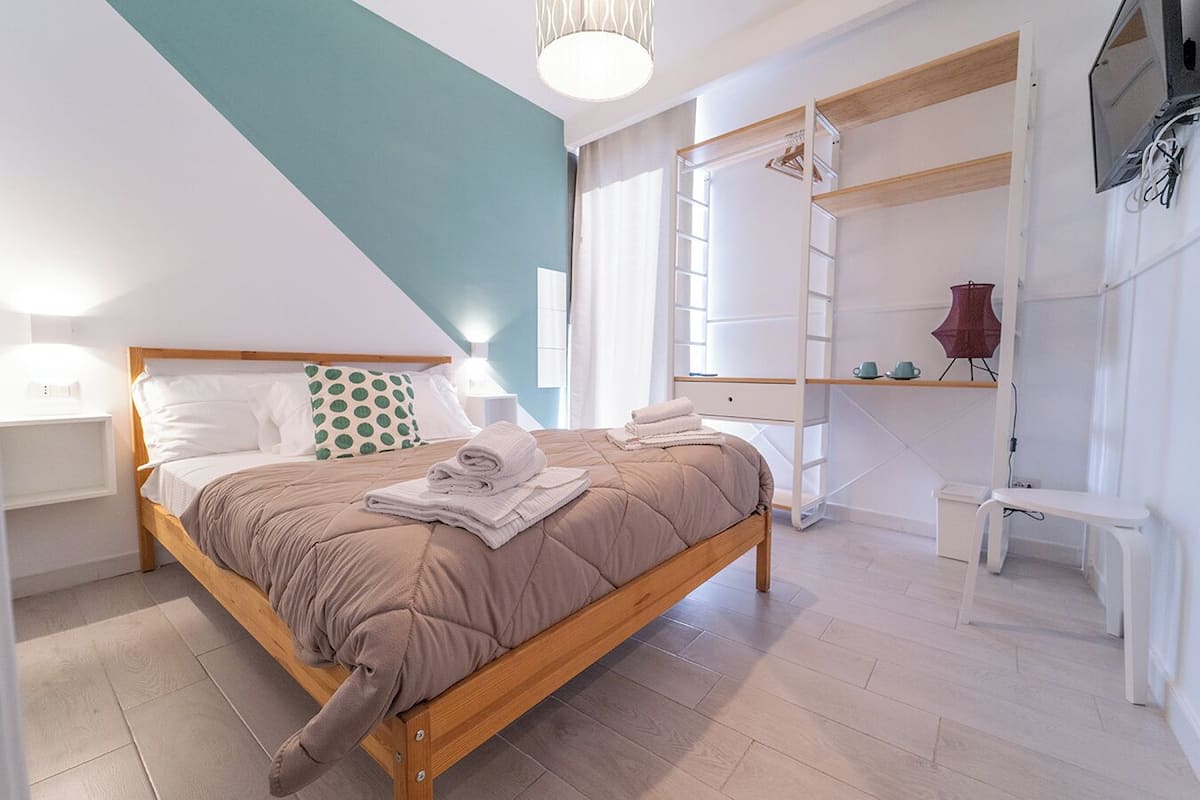 A modern bedroom with a wooden bed, a built-in wardrobe, and a TV mounted on the wall.