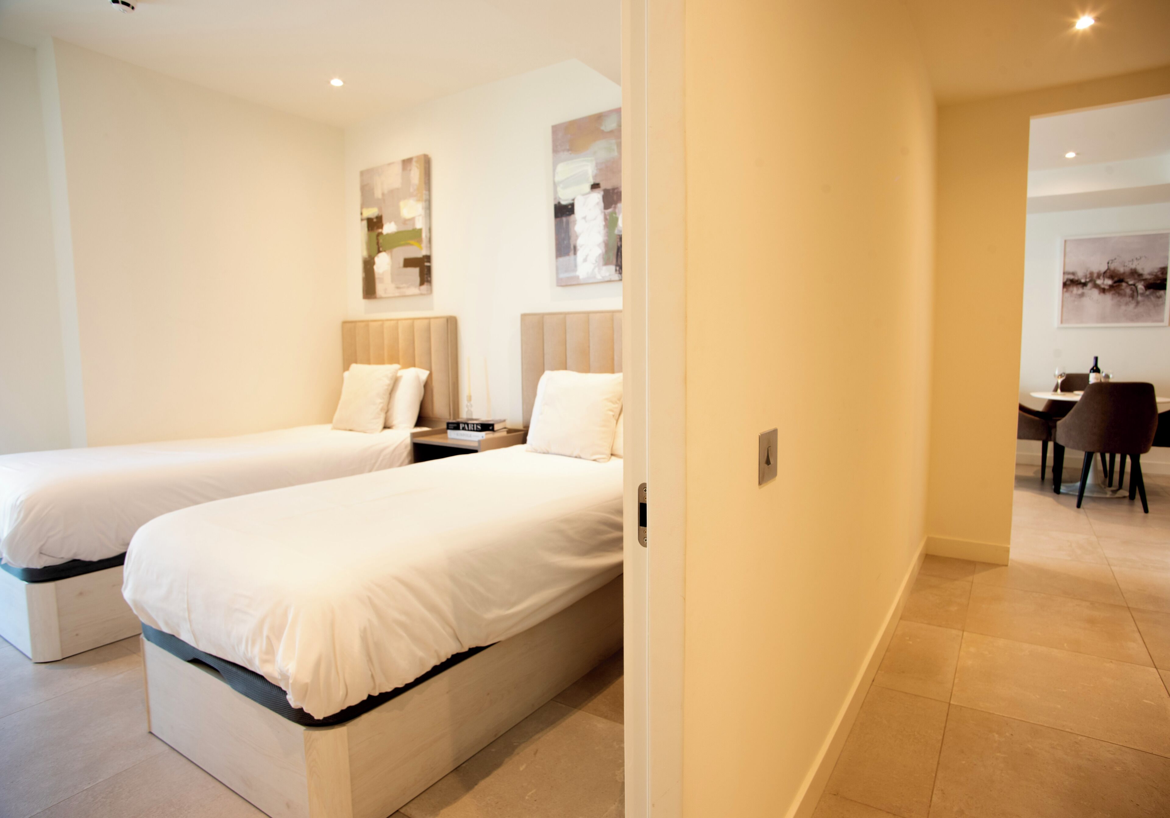 Een hotelkamer met twee éénpersoonsbedden, een tafeltje, een stoel en een bureau met een stoel.