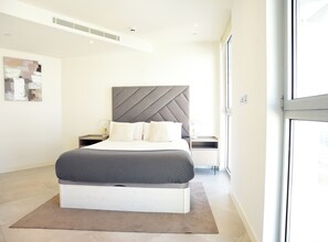 A modern bedroom with a large bed, bedside tables, a headboard, and a window. - Eurocity (Gibraltar)