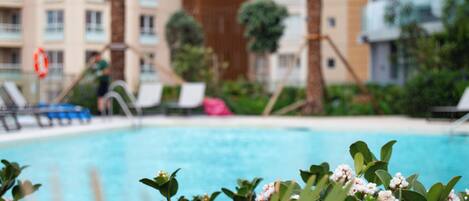 A swimming pool with lounge chairs and palm trees.