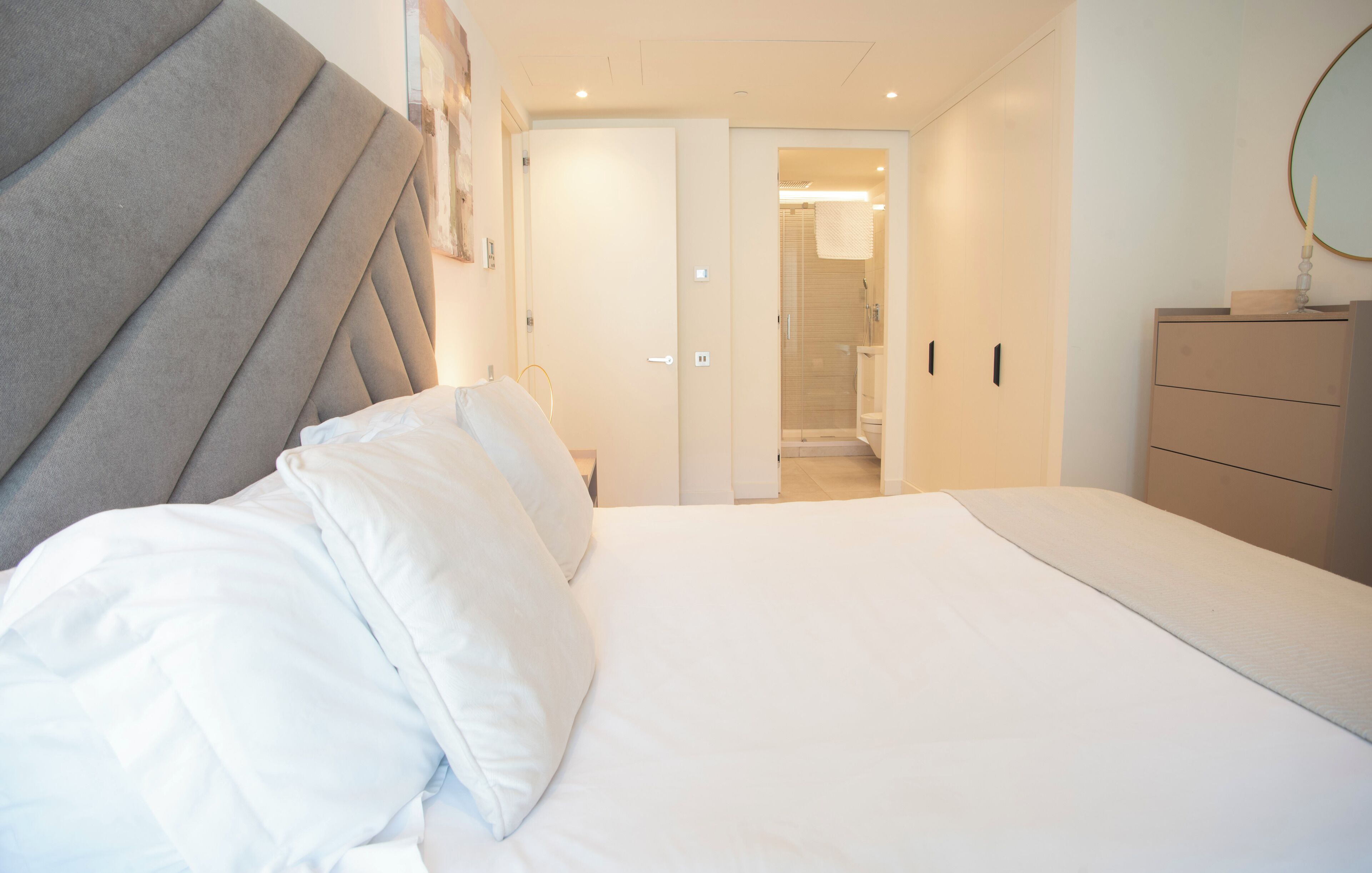 Een slaapkamer met een bed, een kaptafel en een zichtbare badkamer door een open deur.
