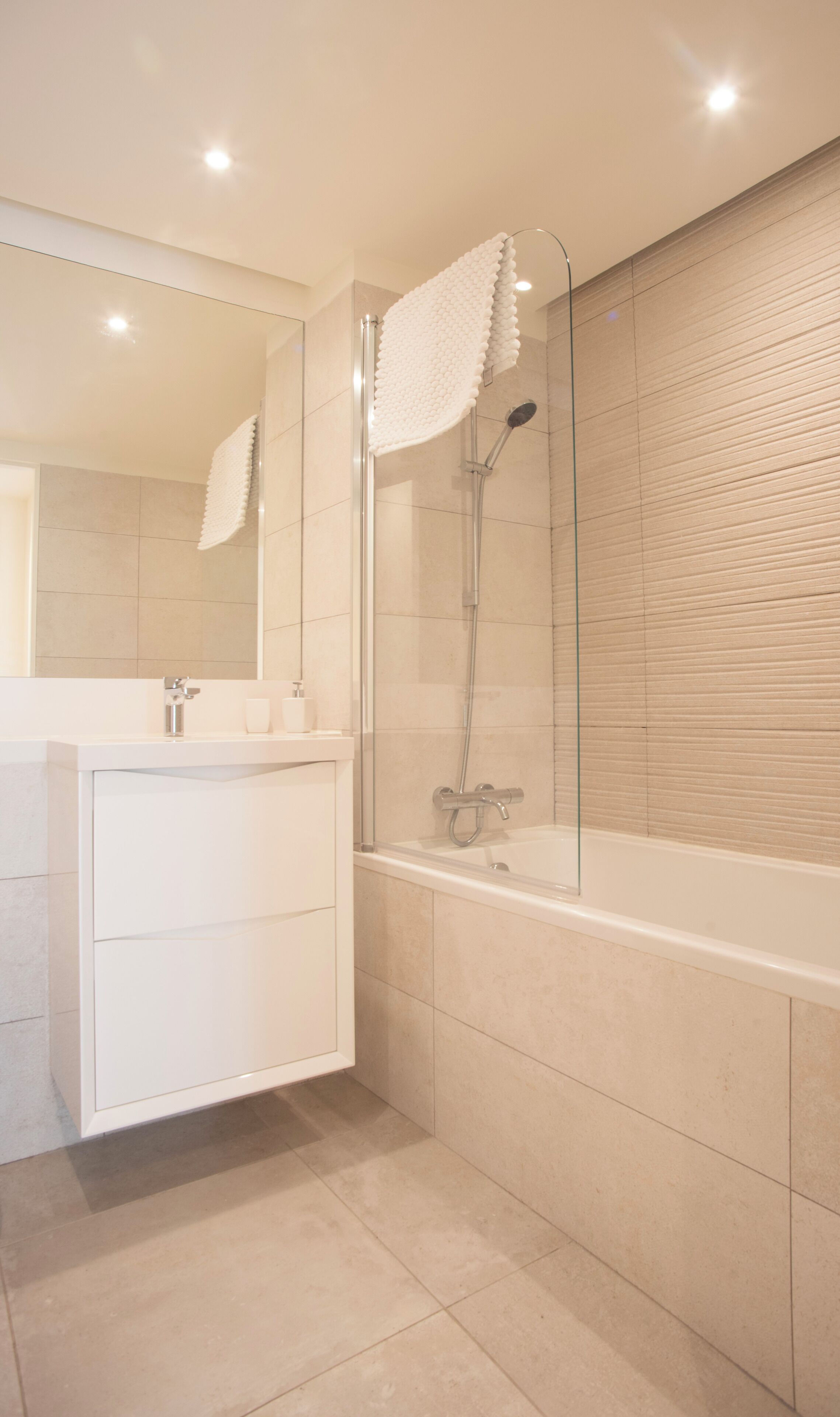 Une salle de bain moderne avec une douche à parois de verre, un meuble-lavabo blanc et un grand miroir.