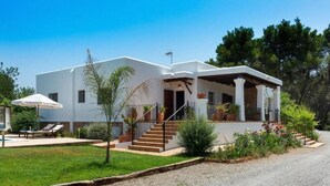 A two-story white house with a covered porch, a small garden, and a gravel driveway. - New! Villa Can Curreu III - Santa Gertrudis (Ibiza)
