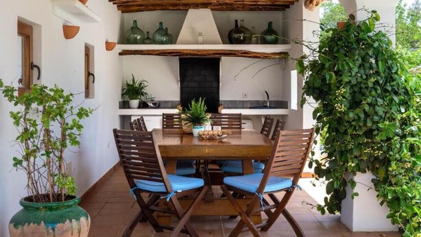 A dining area with a wooden table and chairs, surrounded by shelves with decorative items. - New! Villa Can Curreu III - Santa Gertrudis (Ibiza)