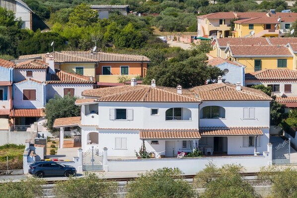 A residential area with terracotta-tiled roofs, white and pastel-colored houses, and a gated entrance.