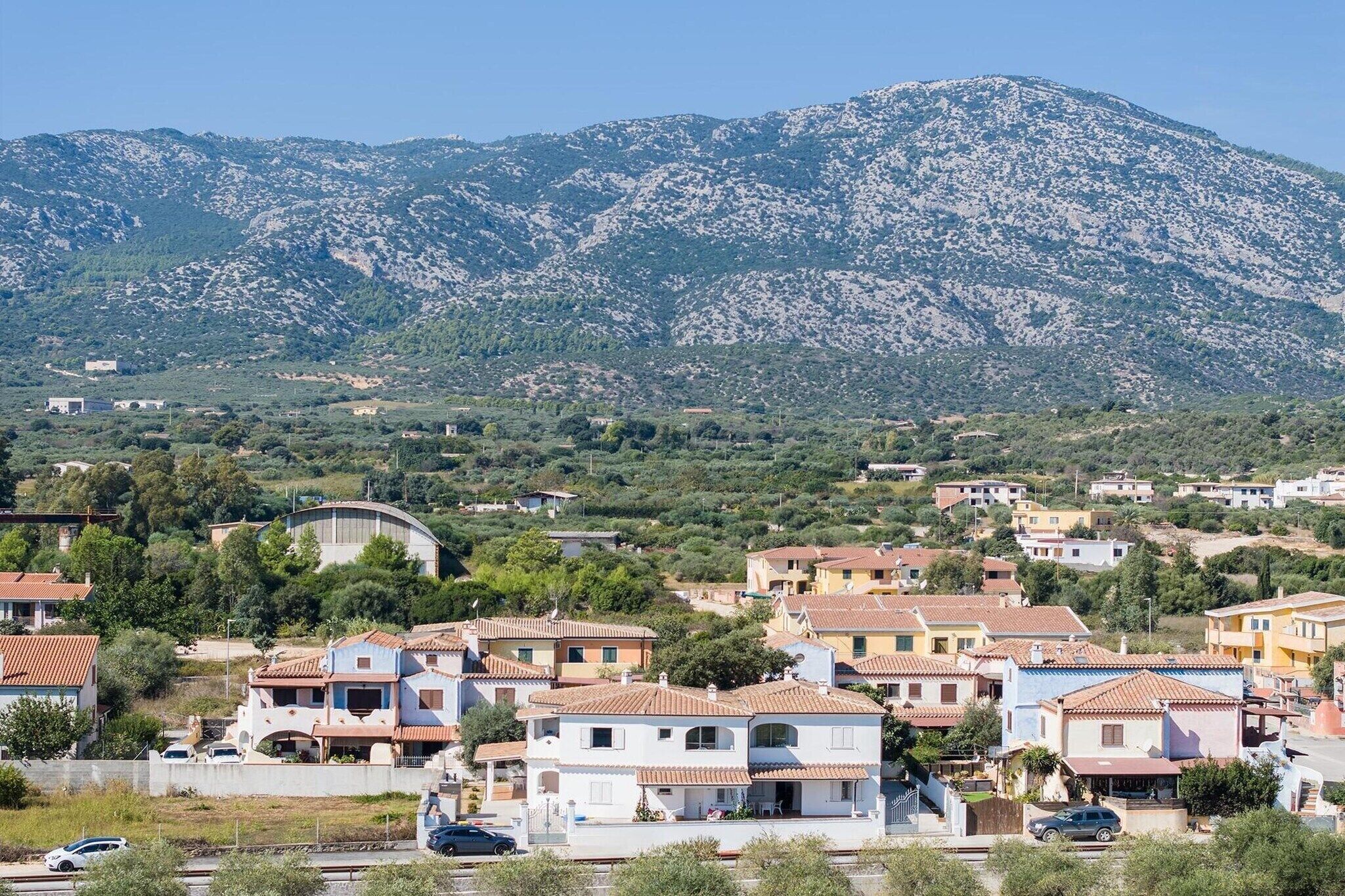 Un quartier résidentiel avec des maisons, une route et une montagne en arrière-plan.