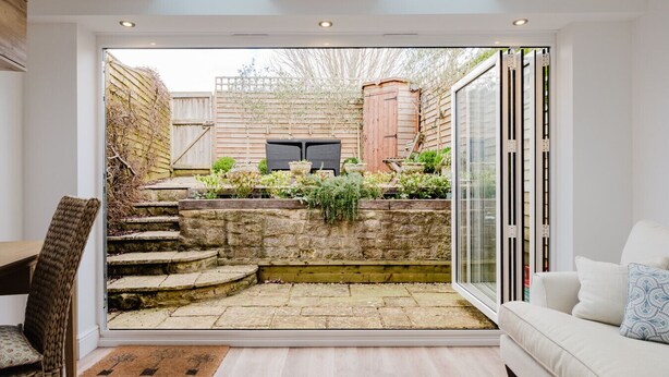 Een moderne patio met stenen trappen, een houten omheining en een zithoek met een bank en een stoel.