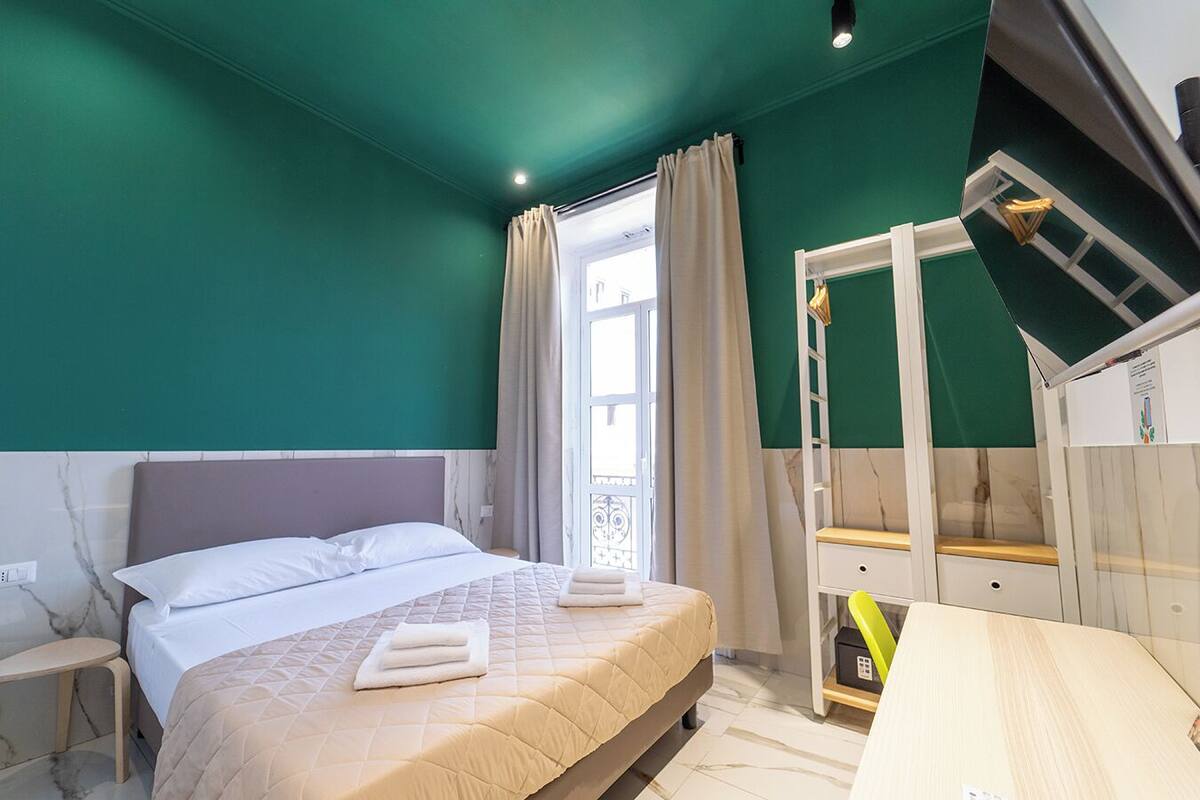 Une chambre à coucher avec un lit, une table de chevet, une fenêtre avec des rideaux et un lit superposé avec une échelle.