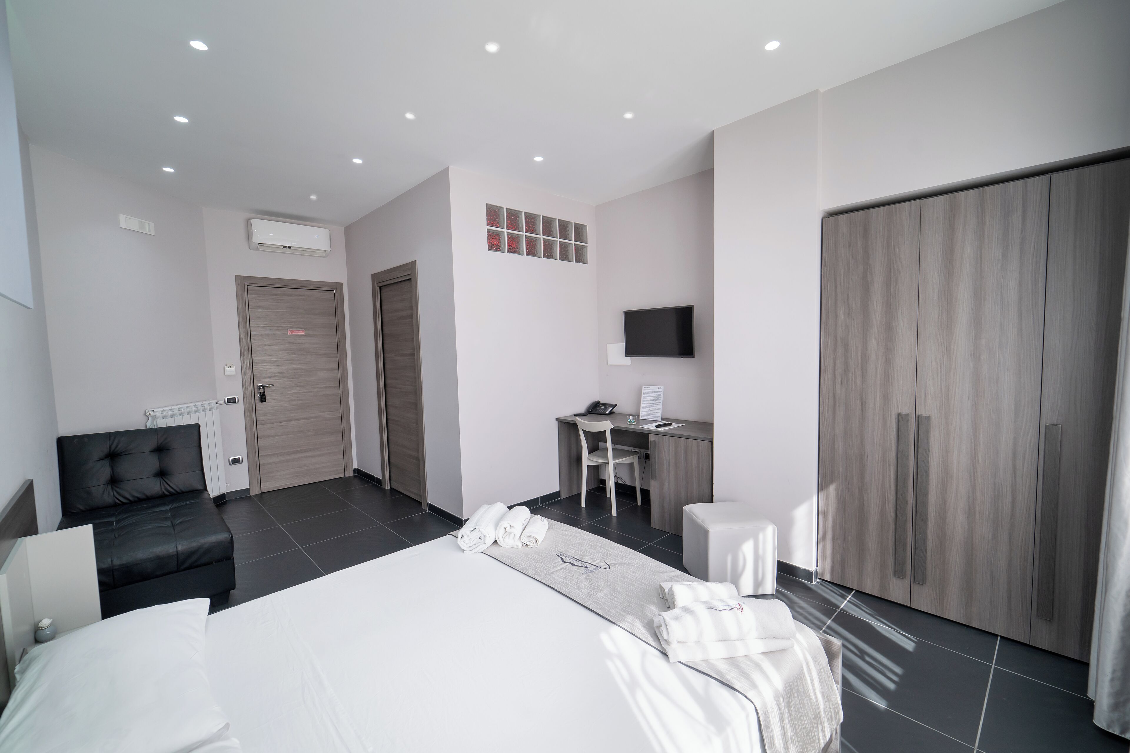 Une chambre d’hôtel moderne équipée d’un grand lit, d’un bureau, d’une chaise, d’une télévision et d’une armoire.
