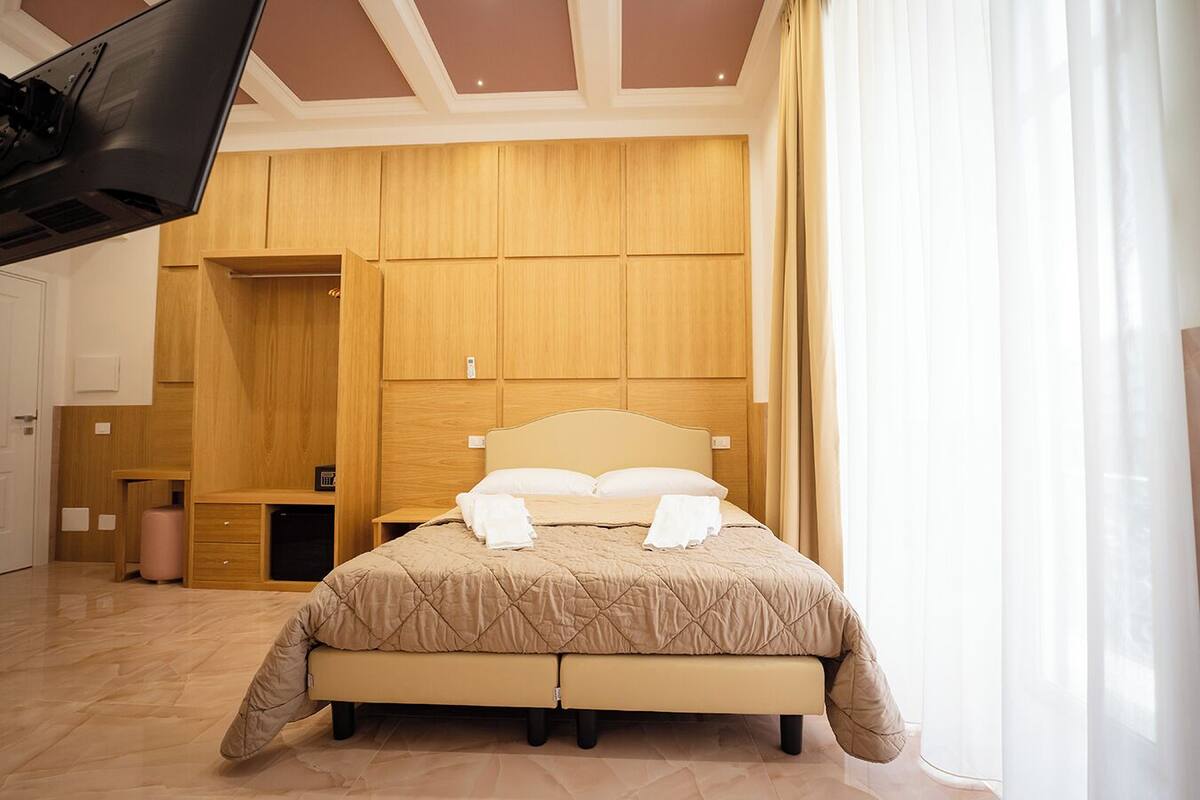 Une chambre à coucher avec un lit, une armoire en bois et un téléviseur fixé au mur.