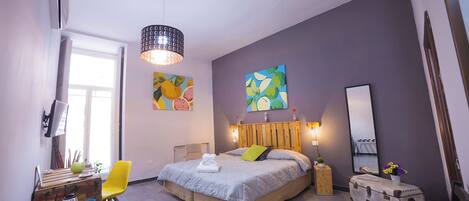 Un dormitorio moderno con cama, mesita de noche, silla y una obra de arte.