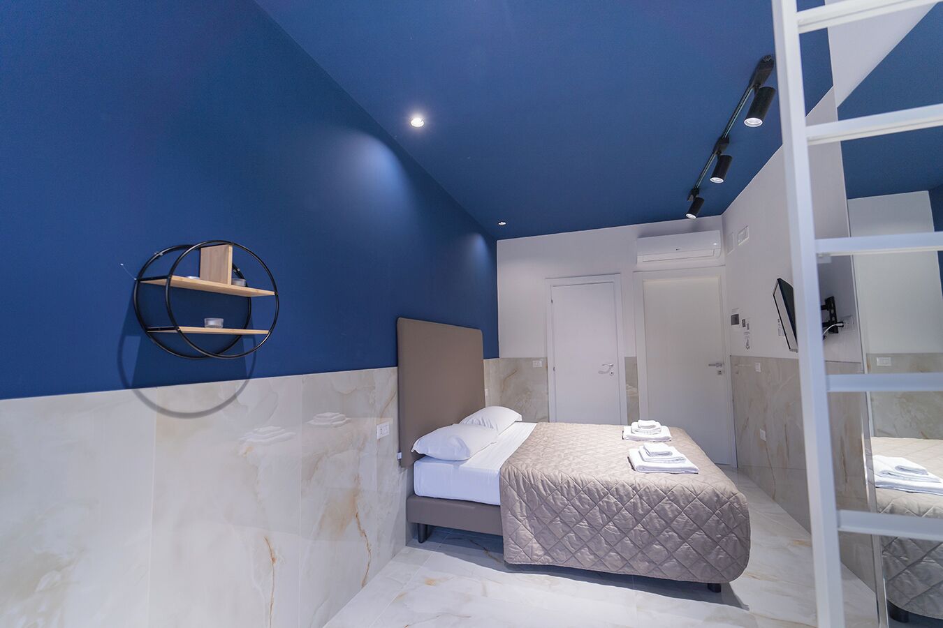 Una habitación de hotel moderna con una cama, un armario empotrado y una estantería circular.