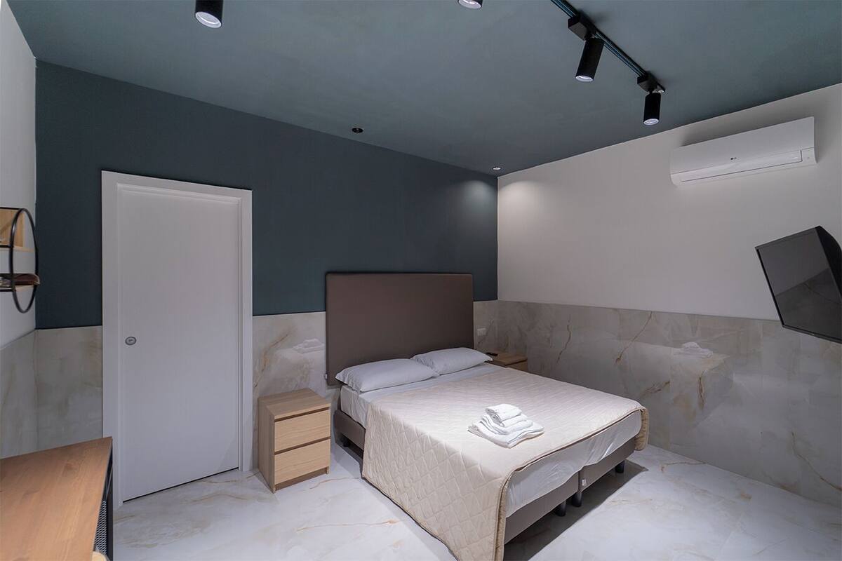 Une chambre moderne avec un lit, des tables de chevet, une armoire et un luminaire au plafond.