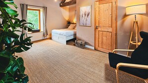 A bedroom with a bed, a chair, a lamp, and a window with curtains. - Family-Friendly 1BR w/ Garden View + Hot Tub (Étivey)