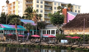 Un restaurant situé au bord de l’eau, avec une terrasse et une vue sur un bâtiment en arrière-plan.