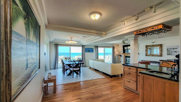 A spacious living area with a dining table, a sofa, and a kitchen with wooden cabinets and a countertop. - Oceanside Manor – Your Big, Pet-Friendly Retreat (Surf City)
