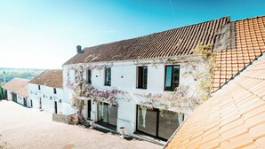Un bâtiment blanc avec un toit en tuiles, de grandes fenêtres et une cour intérieure.