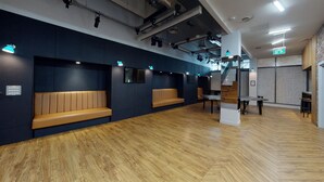 Eine großzügige Lobby mit Holzboden, dunklen Wänden und Sitzbereichen.