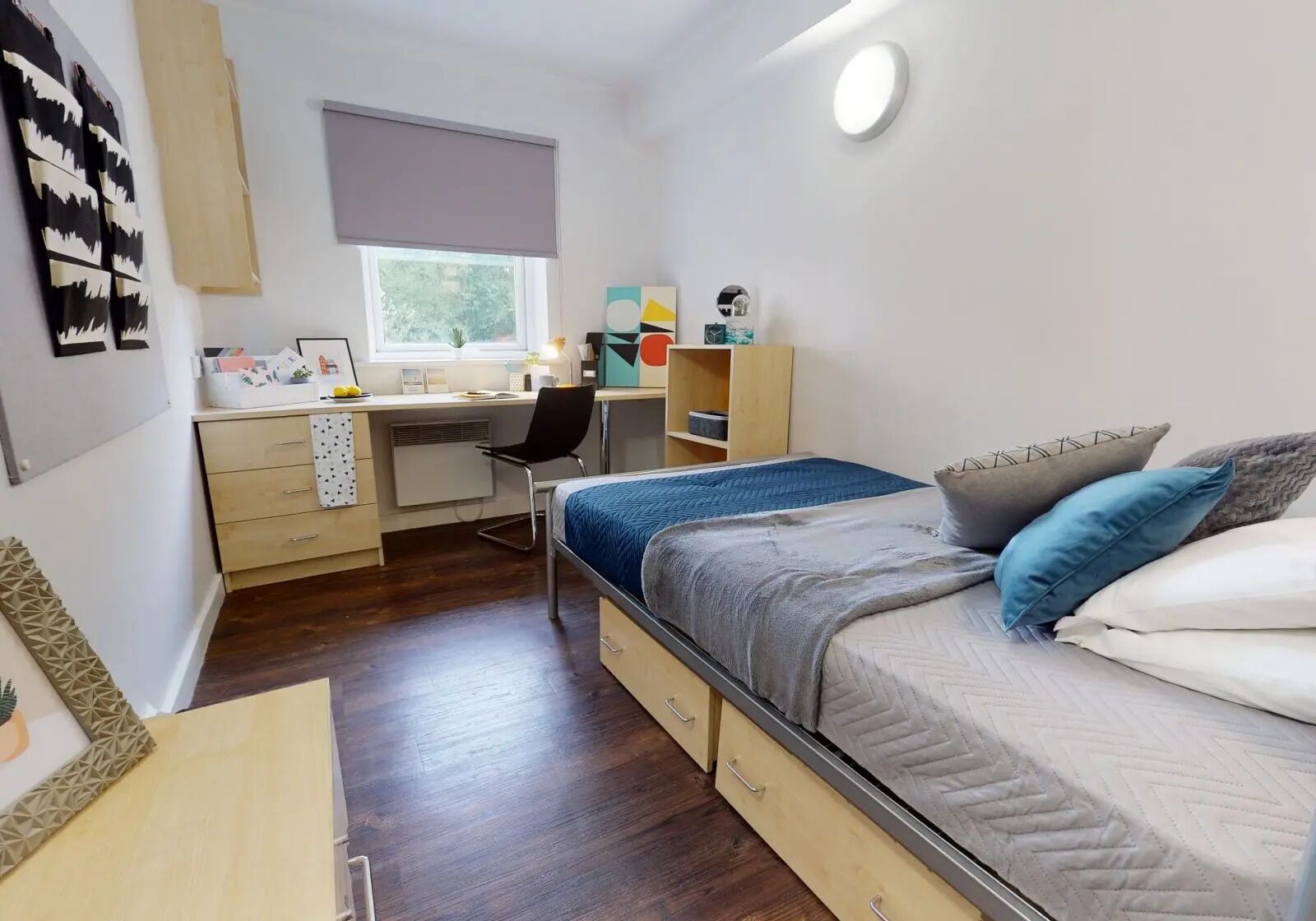A bedroom with a bed, a desk, a chair, a window, and a wardrobe.