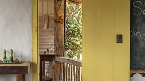 Ein rustikaler Raum mit einer Holztür, die auf einen Balkon führt, einer Tafel mit Schrift und einem kleinen Tisch mit Salz- und Pfefferdosen.