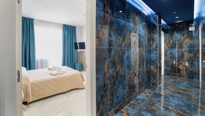 A modern hotel room with a bed, a large mirror, and a marble wall. - P.C. BOUTIQUE H. LIFESTYLE NAPOLI CENTRO by ClaPa Group Dislocated Hospitality (Naples)