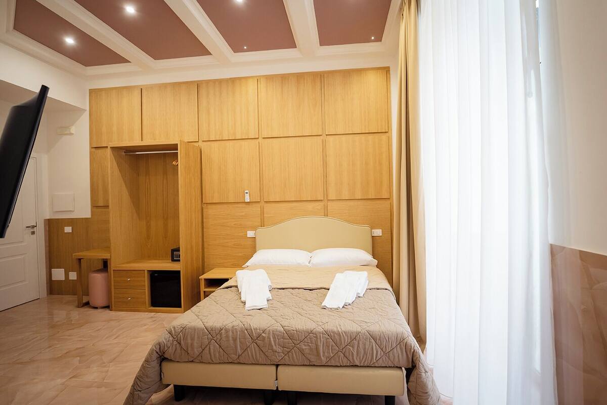 A bedroom with a bed, wooden wardrobe, and a bench.