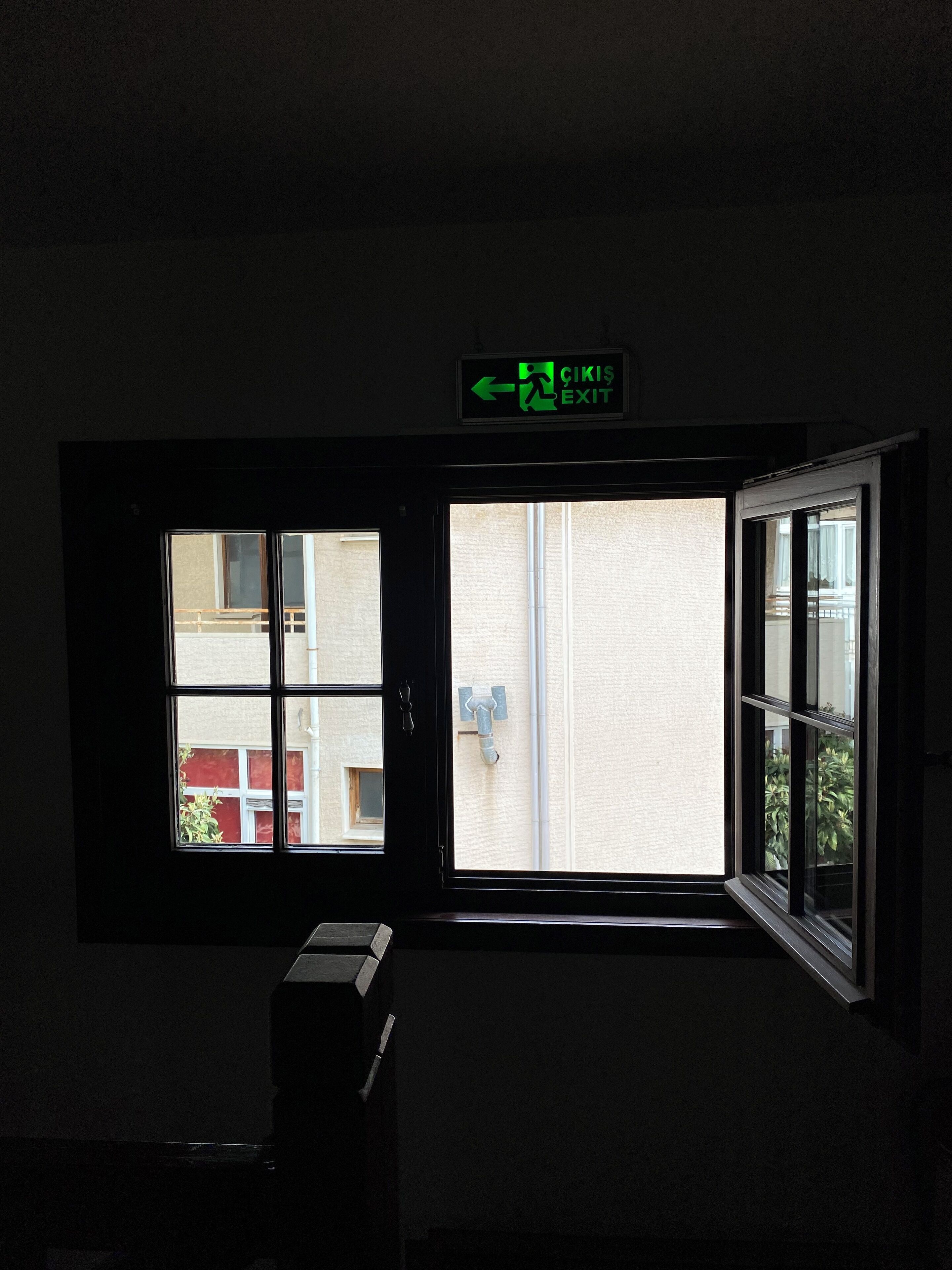 Une pièce avec une fenêtre, une porte et un panneau de signalisation vert indiquant la sortie.