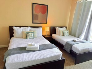 Une chambre d’hôtel avec deux lits, une table de chevet avec une lampe et un tableau au mur.