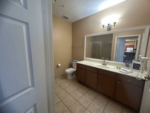 A bathroom with a toilet, sink, and mirror. - Charming condo Just a few minutes from Disney! (Kissimmee)